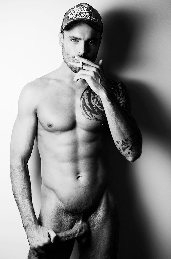 Photo d'un bel homme nu gay lascard avec une énorme bite. Il est tatoué et bien foutu, musclé et charmant.