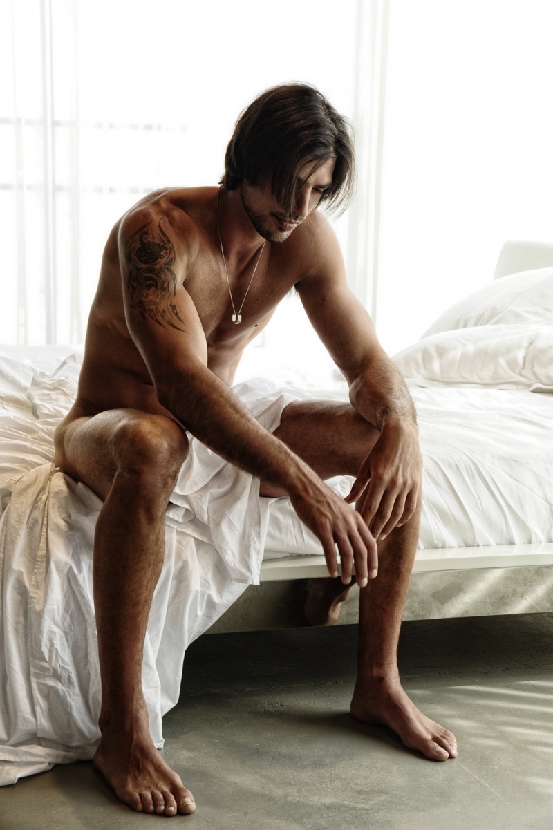Un homme nu tatoué dans un lit blanc du 14 mars 2013