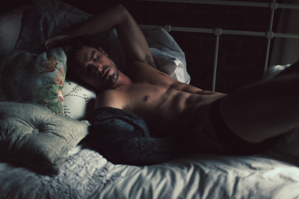 Une photo artistique d’un homme nu sur un lit